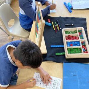 elementary students work with montessori materials to learn math concepts