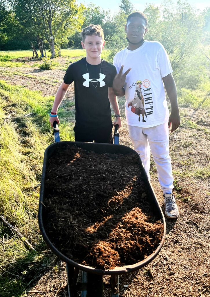 two students haul mulch outdoors